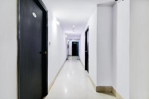 a hallway with white walls and a black door at FabHotel 1 Lovelock in Ballygunge