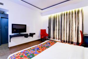 a bedroom with a bed and a television and a red chair at FabHotel 1 Lovelock in Ballygunge