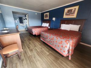 Habitación de hotel con 2 camas y escritorio en Guest House Motel, en Carthage