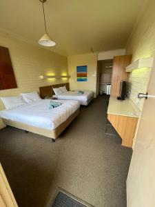 Habitación de hotel con 2 camas y escritorio en Opal Inn Hotel, Motel, Caravan Park en Coober Pedy