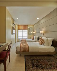 a large bedroom with two beds and a table at Residency Hotel Fort in Mumbai