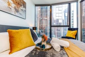 una camera da letto con un letto con cuscini gialli e un tavolo di Sky High 180 Panoramic Views-Prime CBD,Pool & Gym a Melbourne