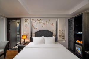 a bedroom with a large white bed and flowers on the wall at Amara Hanoi Hotel and Spa in Hanoi