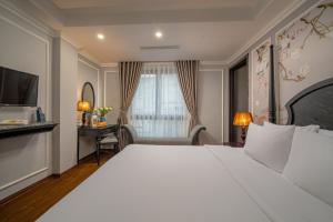 a hotel room with a large bed and a desk at Amara Hanoi Hotel and Spa in Hanoi