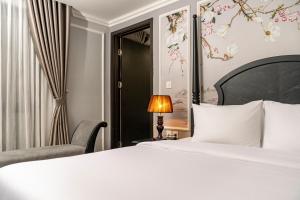 a bedroom with a white bed and a chair at Amara Hanoi Hotel and Spa in Hanoi