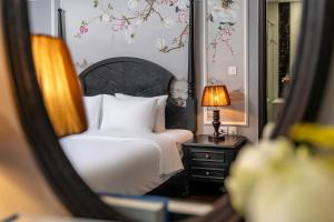 a reflection of a bedroom with a bed and a lamp at Amara Hanoi Hotel and Spa in Hanoi