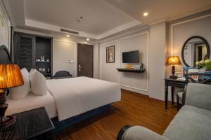 a hotel room with a large white bed and a desk at Amara Hanoi Hotel and Spa in Hanoi
