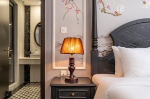 a lamp on a night stand next to a bed at Amara Hanoi Hotel and Spa in Hanoi