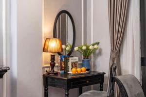 a table with a lamp and a mirror on it at Amara Hanoi Hotel and Spa in Hanoi