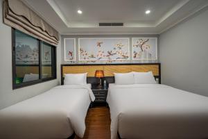two beds in a room with paintings on the walls at Amara Hanoi Hotel and Spa in Hanoi