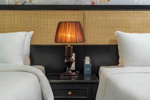 a lamp sitting on a table between two beds at Amara Hanoi Hotel and Spa in Hanoi