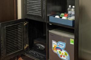 a small refrigerator in a room with a shelf at Amara Hanoi Hotel and Spa in Hanoi