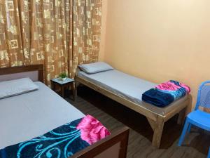 een kamer met 2 bedden, een stoel en een gordijn bij Ritesh BNB in Gangtok