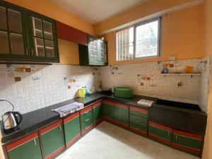 eine Küche mit grünen Schränken und einem Fenster in der Unterkunft Ritesh BNB in Gangtok