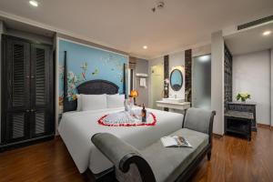 a bedroom with a large white bed and a couch at Amara Hanoi Hotel and Spa in Hanoi