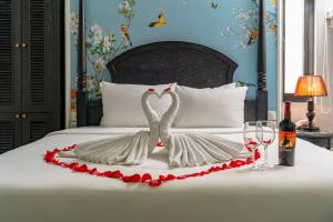 two swans are forming a heart on a bed at Amara Hanoi Hotel and Spa in Hanoi
