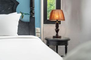 a lamp sitting on a table next to a bed at Amara Hanoi Hotel and Spa in Hanoi