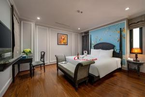 a bedroom with a large bed with a desk and a desk at Amara Hanoi Hotel and Spa in Hanoi