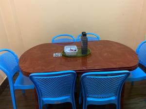 uma mesa de madeira com cadeiras azuis e uma garrafa em Ritesh BNB em Gangtok