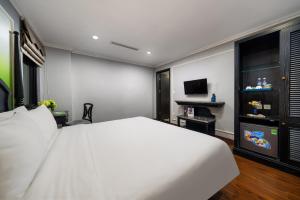 a bedroom with a white bed and a television at Amara Hanoi Hotel and Spa in Hanoi