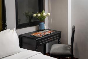 a table with a vase of flowers on it next to a bed at Amara Hanoi Hotel and Spa in Hanoi