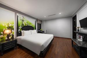a bedroom with a large white bed and a tv at Amara Hanoi Hotel and Spa in Hanoi