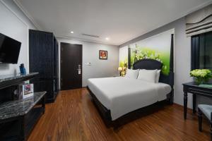 a bedroom with a white bed and a television at Amara Hanoi Hotel and Spa in Hanoi
