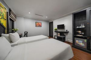 a bedroom with a large white bed and a flat screen tv at Amara Hanoi Hotel and Spa in Hanoi