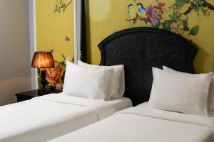 two beds with white pillows in a bedroom at Amara Hanoi Hotel and Spa in Hanoi