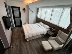 a bedroom with a bed and a chair and a window at RF Hotel – Linsen in Taipei