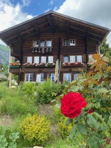 Büehl Lenk في لينك: منزل خشبي أمامه وردة حمراء