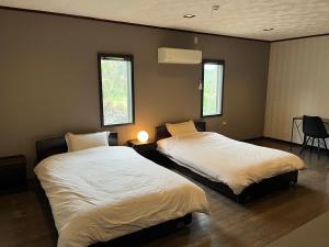 sypialnia z 2 łóżkami i 2 oknami w obiekcie 百合ヶ浜ビーチハウス w mieście Furusato