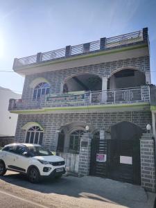 a white car parked in front of a brick building at Gaharwar Home Stay in Rāni Pokhri