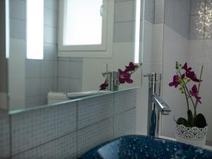 a bathroom with a sink and a mirror and purple flowers at RHOMBUS by the sea in Paleo Tsifliki +78 photos