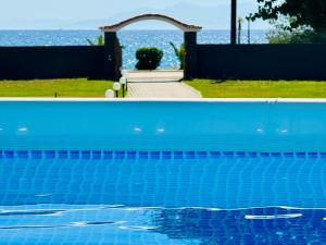 una piscina blu con arco e oceano di Gazonia Family Estate a Skala di Cefalonia