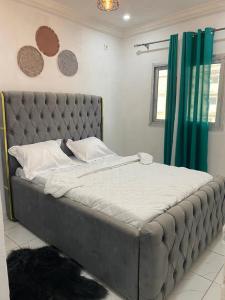 ein großes Bett mit grauem Kopfteil in einem Schlafzimmer in der Unterkunft Studio meublé à bas prix (salon, chambre, douche, cuisine) in Yasika