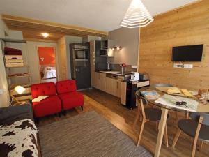 Les Berlicants في ميجو: غرفة معيشة مع أريكة حمراء ومطبخ