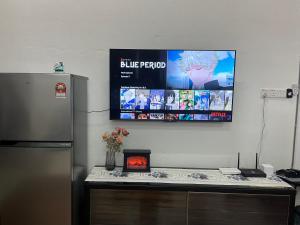 a tv hanging on a wall above a counter with a refrigerator at La Wood Homestay near Kuala Besut Jetty in Kuala Besut