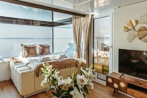 um quarto com uma cama e uma grande janela em Domki na wodzie - Grand HT Houseboats - with sauna, jacuzzi and massage chair em Mielno