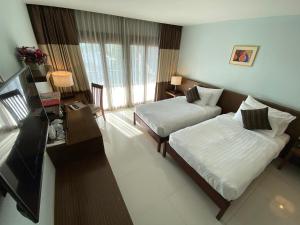 a hotel room with two beds and a television at Siam Triangle Hotel in Chiang Saen