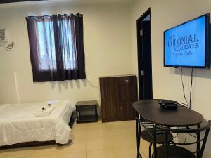 a room with a bed and a table and a television at The Colonial Residences Angeles City in Angeles