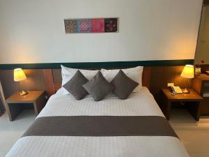 um quarto com uma cama branca com almofadas e 2 candeeiros em Siam Triangle Hotel em Chiang Saen
