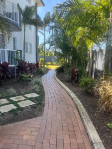 a brick path in front of a house with palm trees at Sea Mist Palms in Gold Coast