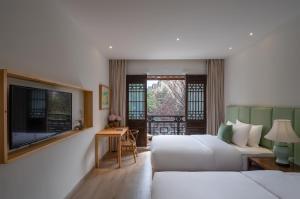 a hotel room with a bed and a television at Mount Emei Heyuan Serene Residence Hot Spring Hotel in Emeishan City