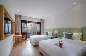 a hotel room with two beds and a television at Mount Emei Heyuan Serene Residence Hot Spring Hotel in Emeishan City
