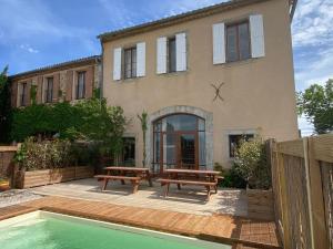 a house with two benches and a pool in front of it at Maison, canal du midi piscine in Homps