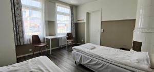 een slaapkamer met 2 bedden, een bureau en 2 stoelen bij Villa Nostan in Nybro
