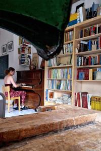 una mujer sentada en un piano en una habitación con libros en Lapland Old School, en Muonio