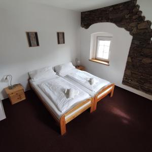 a bedroom with a bed with white sheets and a window at Chata SKI in Loučná pod Klínovcem