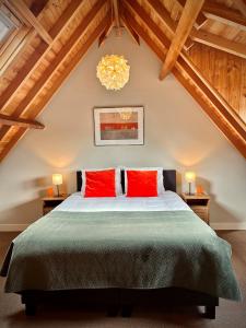 a bedroom with a large bed with two red pillows at Natuurlogies Buurse Buiten in Haaksbergen